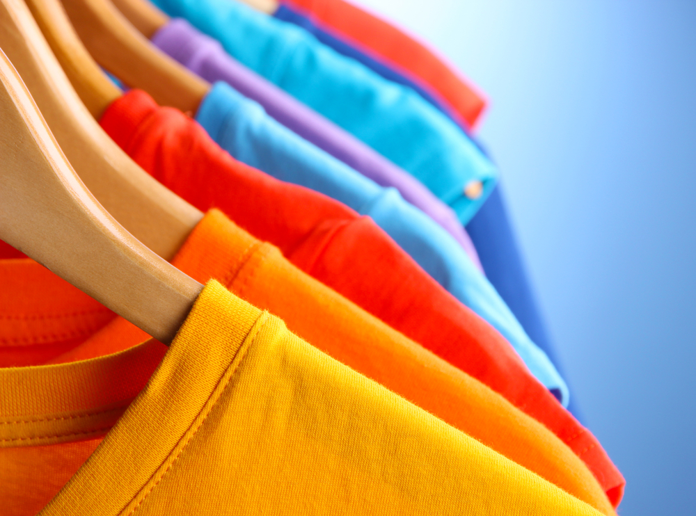 Lots of T-shirts on hangers on blue background